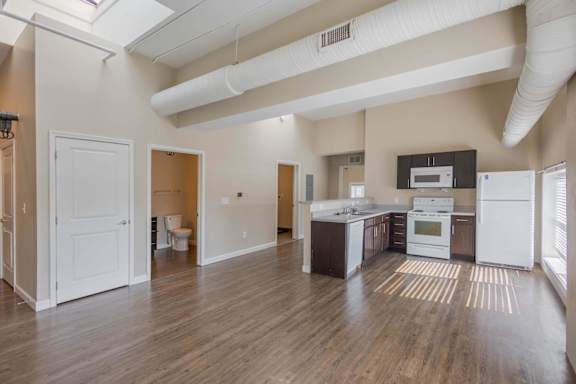 A kitchen with white appliances and wooden floors.