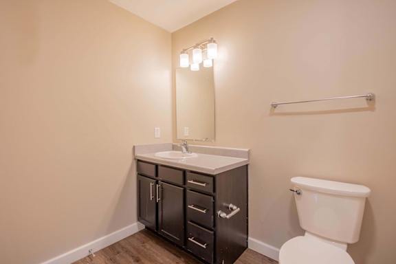 A bathroom with a white toilet and a sink with a cabinet underneath it.