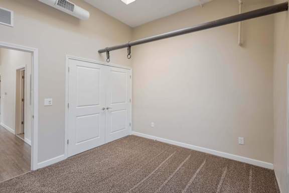 A room with a white door and a brown carpet.