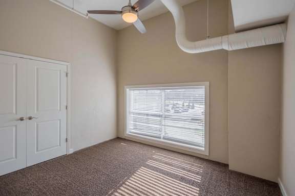 A room with a ceiling fan and a window with blinds.