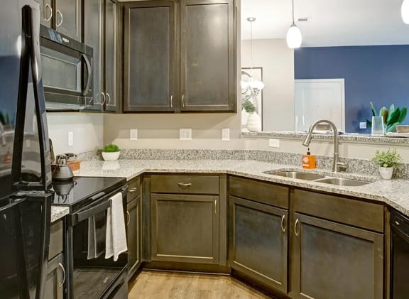 Kitchen with granite counter tops, wood-like flooring, dark color cabinets, black appliances at Ascent at Mallard Creek Apartment Homes, 28262