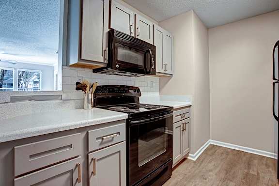 a kitchen with white cabinets and a black stove and a microwave