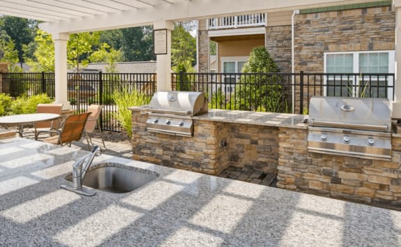 Outdoor kitchen with grills and seating area at Enclave at Bailes Ridge Apartment Homes, 29707