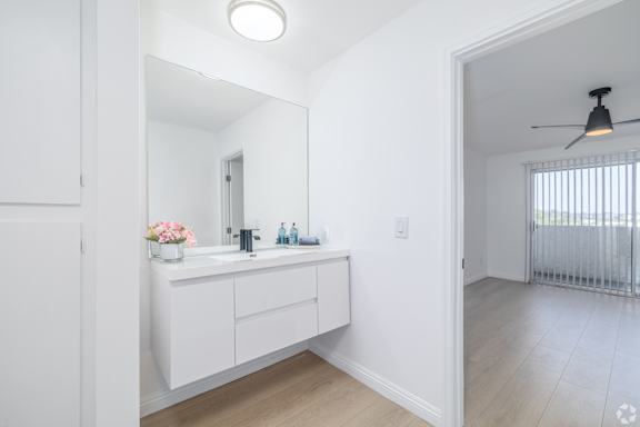 A white bathroom with a vanity and a mirror.