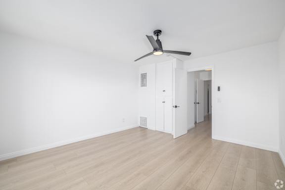 A room with a ceiling fan and wooden flooring.