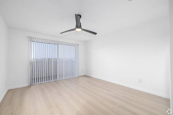 A room with a ceiling fan and a window with blinds.