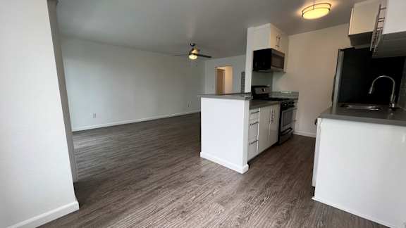 A kitchen with white cabinets and a wooden floor.