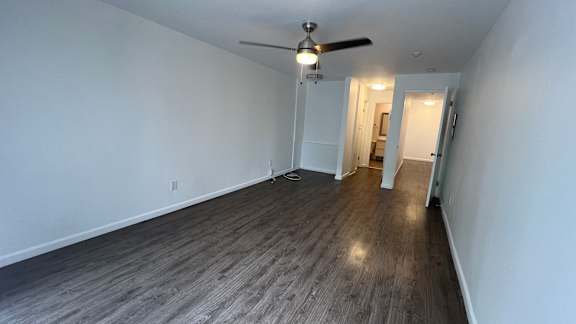 A room with a ceiling fan and wooden flooring.