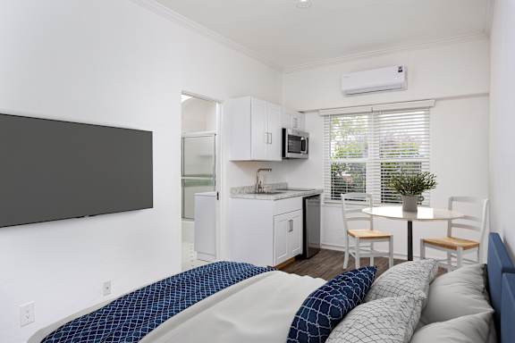 A bedroom with a bed and a small kitchenette.