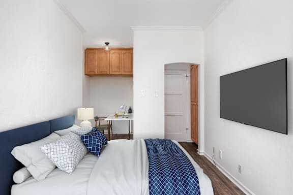 A bedroom with a bed, a lamp, a cabinet, and a door.