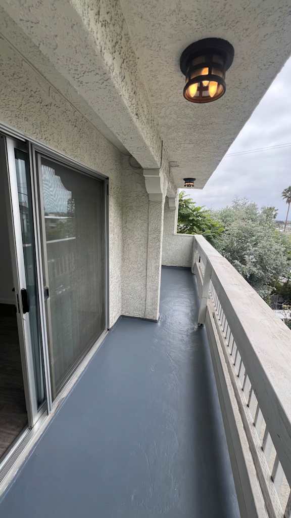 A balcony with a grey floor and a white railing.