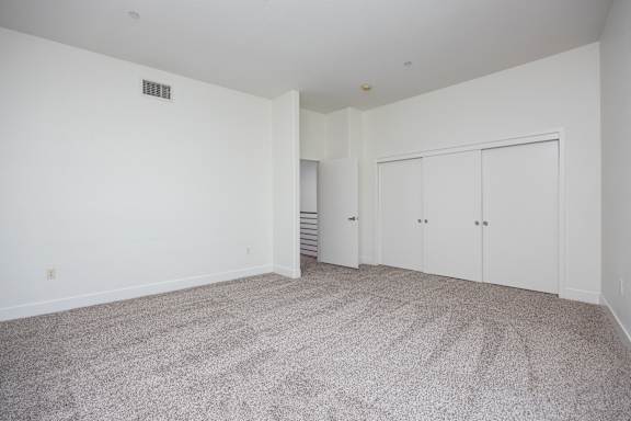 a spacious living room with carpet and white walls