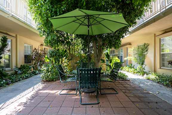 a patio with a green umbrella and a table and chairs