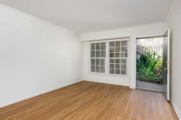 a living room with white walls and a door to a garden
