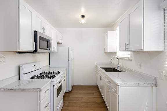 an all white kitchen with white cabinets and white appliances and white counter tops