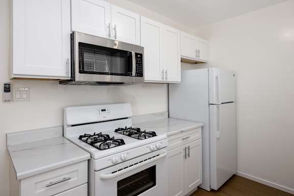 an empty kitchen with white appliances and a microwave and refrigerator
