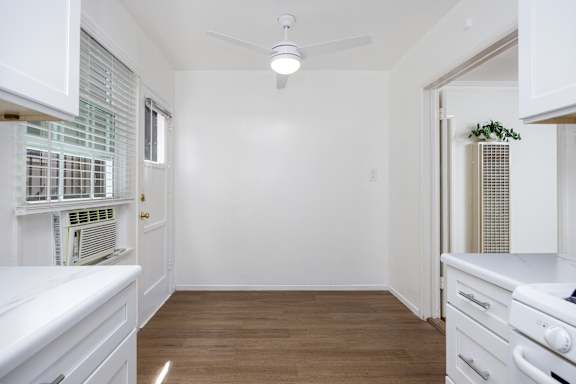a renovated kitchen with white cabinets and a white ceiling fan