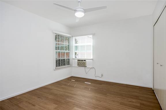 a living room with white walls and wood floors and a window
