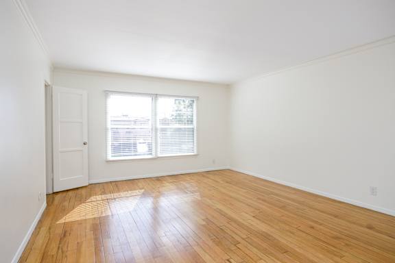 an empty living room with wood floors and a window