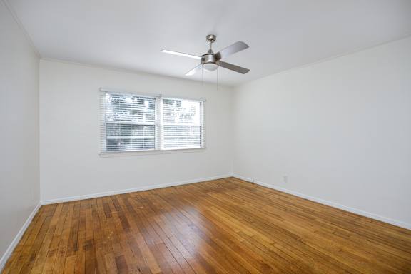 an empty living room with wood floors and a ceiling fan