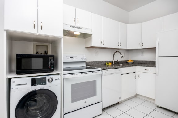 a kitchen with white cabinets and appliances and a washing machine