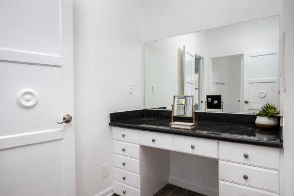 a white bathroom with a black counter top and a mirror
