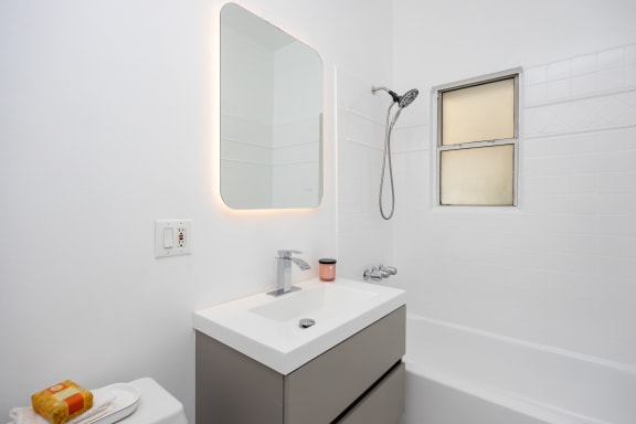 a white bathroom with a sink and shower and a mirror