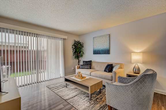 spacious living room with couch and chair and sliding glass door to patio