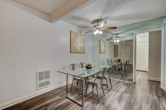 a dining room with a glass table and chairs and a ceiling fan