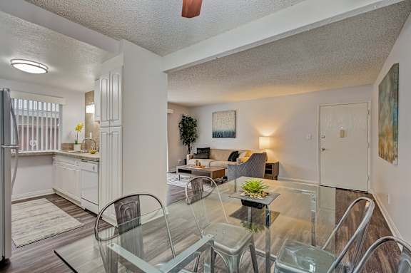 a living room and dining room with a glass table and chairs