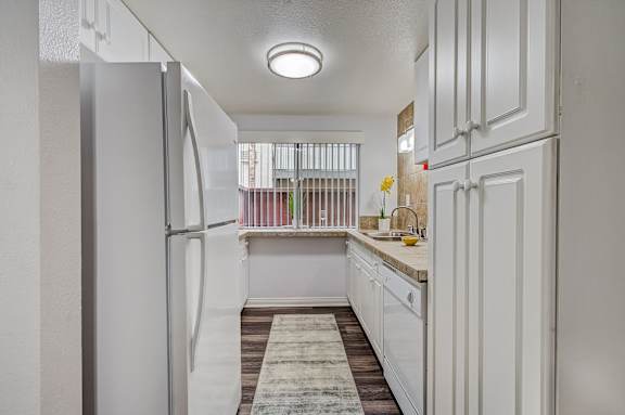 a white kitchen with white cabinets and a white refrigerator