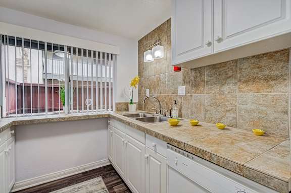 a kitchen with white cabinets and a sink and a window