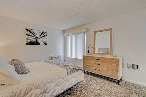 a bedroom with a bed and a dresser and a window