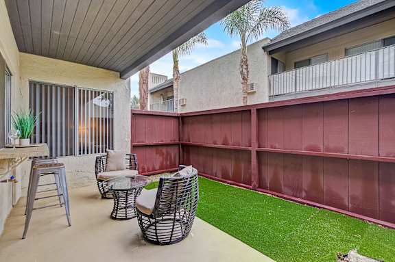 a patio with chairs and a table and grass
