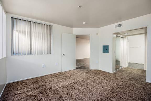 an empty living room with carpet and a door to a hallway
