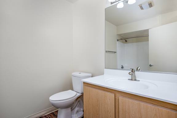 an empty bathroom with a sink toilet and mirror