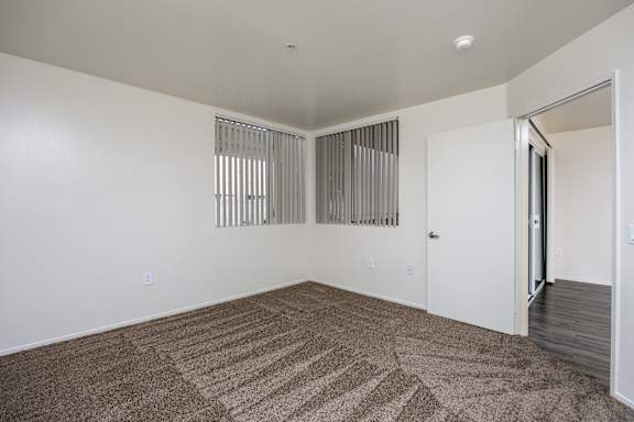 a spacious living room with carpet and a door to a bedroom