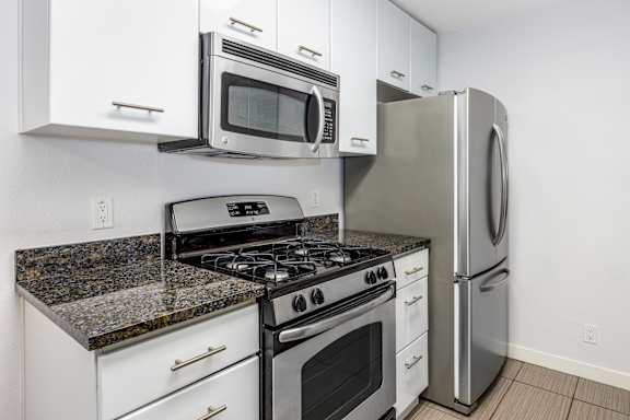 a kitchen with white cabinets and stainless steel appliances and a refrigerator