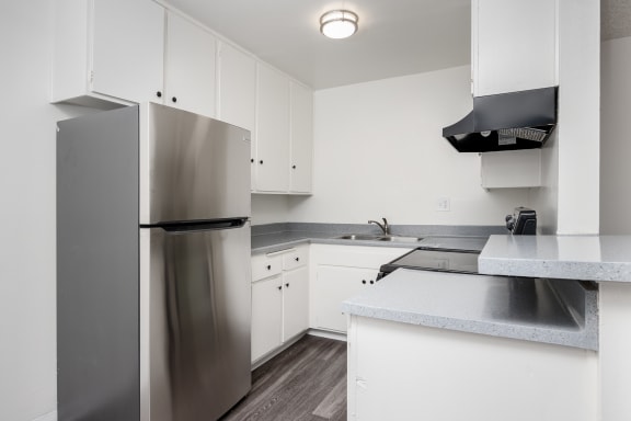 a kitchen with white cabinets and a stainless steel refrigerator