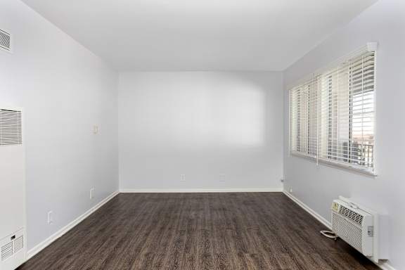 an empty room with white walls and wood floors and a window