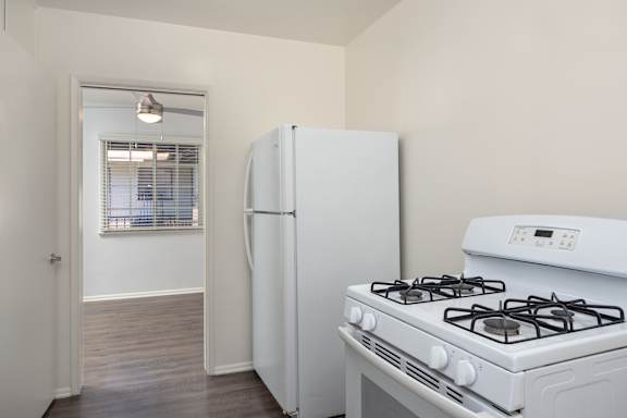 an empty kitchen with a white stove and refrigerator