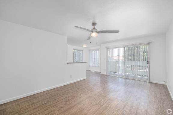 A spacious room with a ceiling fan and sliding glass doors.