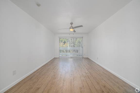 A room with a ceiling fan and wooden flooring.