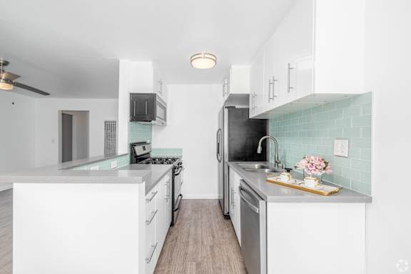 A kitchen with white cabinets and a green backsplash.
