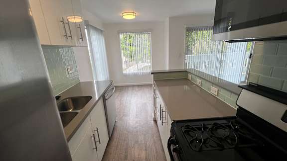 A kitchen with a stove, sink, and cabinets.