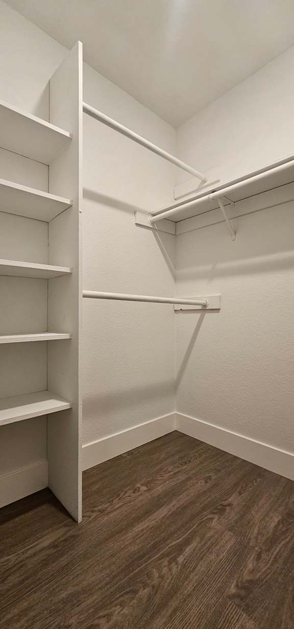 A white shelving unit with four shelves is mounted on a wall.