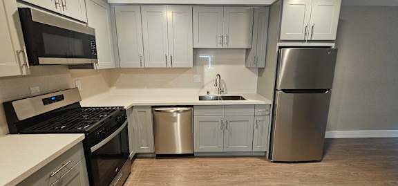 A kitchen with white cabinets and a stainless steel refrigerator.