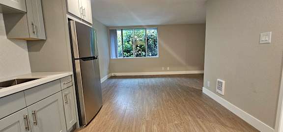 A kitchen with a refrigerator and wooden floors.