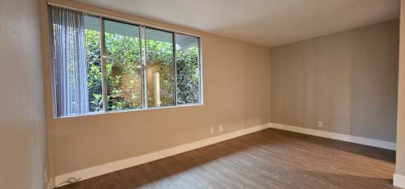 A room with a large window and wooden flooring.