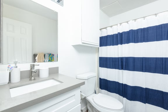a white bathroom with a blue and white shower curtain